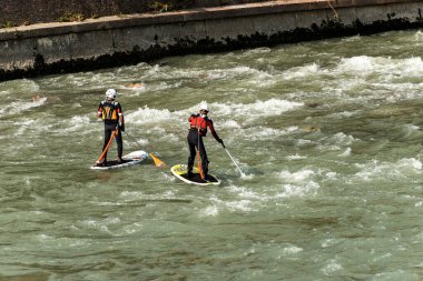 İki adam Stand up Paddleboard (SUP) ile Verona şehir merkezindeki Adige nehrinde kürek çekiyorlar. Veneto, İtalya, Avrupa