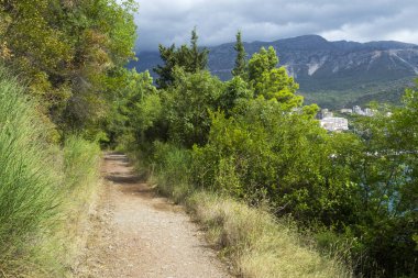 Denize yakın dağlarda bir patika. Bulutlu bir günde yaz