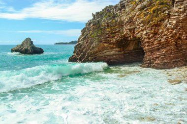 Deniz manzaralı. Dalgalar taş sahilde break. Taş taş ve katmanlı yapısı, deniz köpüğü ve sprey dalga.