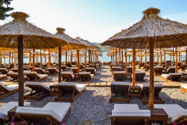 Yumuşak şezlonglar ve güneş plaj ile hasır şemsiyeler. Adriyatik kıyısı. Yaz. İnsanlar.