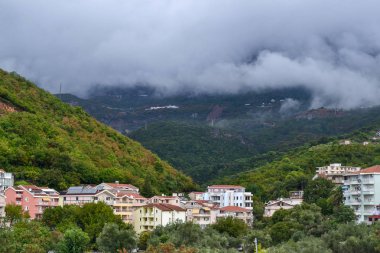 Becici, Karadağ, şehir ve dağ manzarası. Şehrin üzerinde alçak beyaz bulutlar