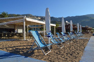 Bir sürü plaj sandalyeleri ve sahilde katlanmış şemsiye.