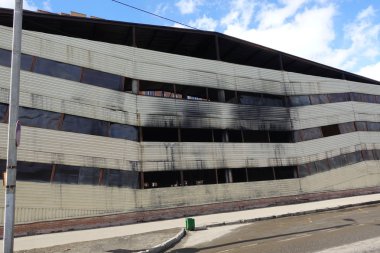 Yangından sonra çok katlı otopark. İçinde yanmış arabalar ile kopya-karanlık pencereler