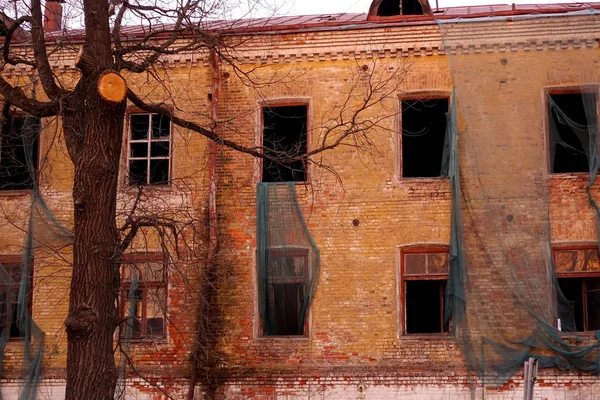 Empty destroyed building with broken windows. Pink sky Sunset. Photo in red colors. The oppressive atmosphere of destruction. Scenery for a horror movie — Stock Photo, Image