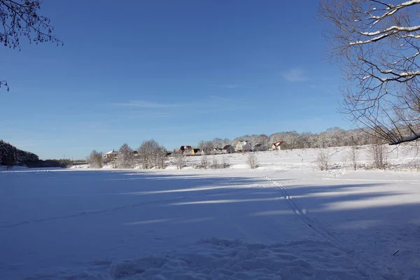 Hermoso paisaje de invierno. Pueblo cerca del bosque. Cielo azul y campo nevado. Día soleado helado. Rusia — Foto de Stock