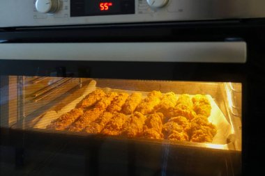 Elektrikli fırında bir fırın tepsisine taze pişmiş tavuk fileto. Tavuk külçeleri pişiriyorum. Serisi.