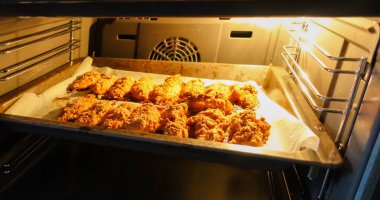 Elektrikli fırında bir fırın tepsisine taze pişmiş tavuk fileto. Tavuk külçeleri pişiriyorum. Serisi.