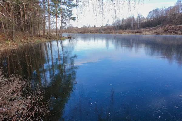Hielo azul en la superficie de un lago forestal. La nieve aún no ha caído. Invierno temprano — Foto de Stock