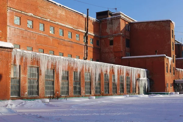The old factory of the Soviet period of red brick in the winter. Big icicles on the roof. Winter. The Moscow Region. Russia — Stock Photo, Image