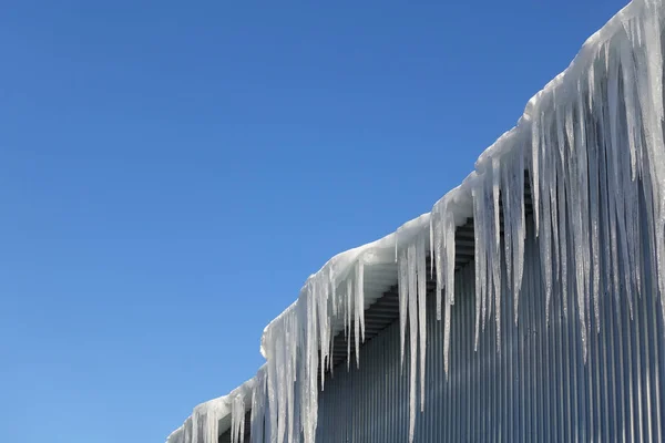 Icicles longos, grandes e perigosos em um telhado de casa de tijolo — Fotografia de Stock