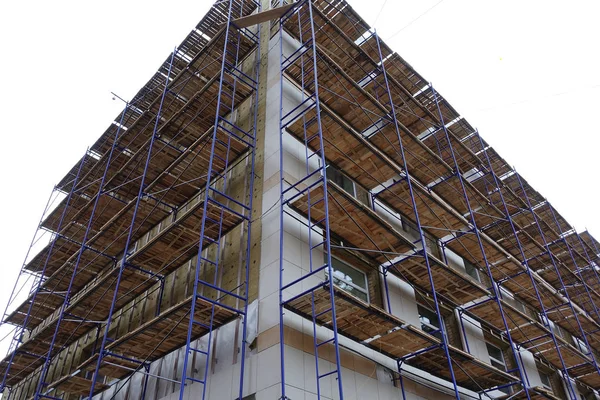 Steigers rond een hoogbouw. Reparatiewerkzaamheden. Renovatie van het gebouw — Stockfoto