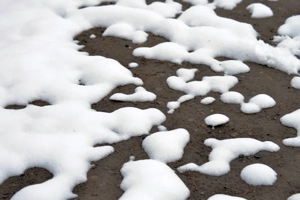Winter background. The snow is melting and looking through the ground. — Stock Photo, Image