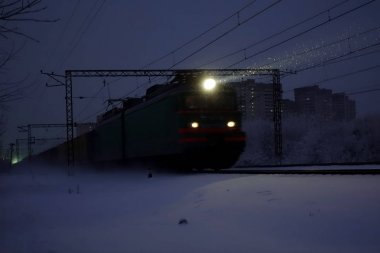 Gece yük treni. Farlar ve lokomotif farlar düşen karı aydınlatır. Rusya.