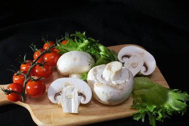 Organik mantarlar. Champignon. Marul, çeri domates. Salata için malzemeler. Sağlıklı yiyecekler. Siyah arka planda