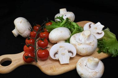 Organik mantarlar. Champignon. Marul, çeri domates. Salata için malzemeler. Sağlıklı yiyecekler. Siyah arka planda