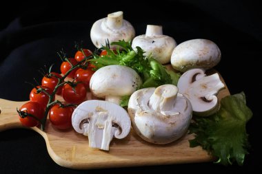 Organik mantarlar. Champignon. Marul, çeri domates. Salata için malzemeler. Sağlıklı yiyecekler. Siyah arka planda