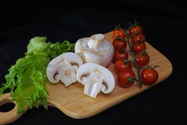 Organik mantarlar. Champignon. Marul, çeri domates. Salata için malzemeler. Sağlıklı yiyecekler. Siyah arka planda