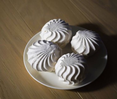 Ahşap bir masa üzerinde kontrast aydınlatma bir tabak üzerinde beyaz marshmallowzephyr Marshmallow dört lezzetli tatlı tatlılar. Kapsama alanı eksikliği. Akşam