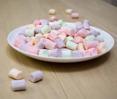Beyaz tabakta çok renkli marshmallowlar.
