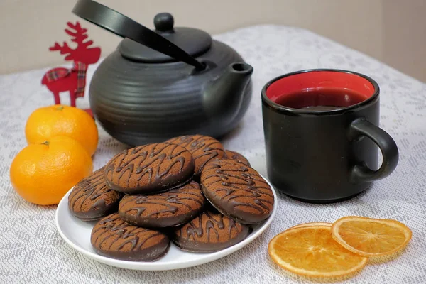 Biscuits au chocolat et ustensiles de thé noir. Coupe et théière. Tranches d'orange séchées. Scène thé . — Photo