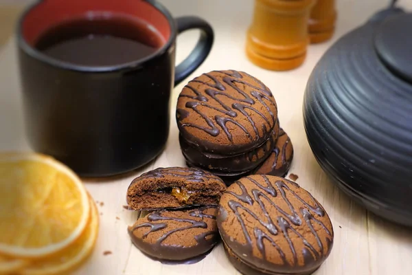 Biscuits au chocolat et ustensiles de thé noir. Coupe et théière. Tranches d'orange séchées. Scène thé . — Photo