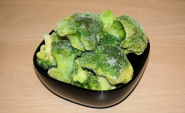 Broccoli freschi congelati in un piatto nero, cibo sano, primo piano — Foto Stock