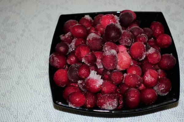 Frysta tranbär i en svart skål bord täckt med vit trasa — Stockfoto