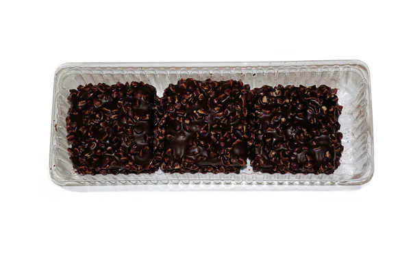 白い背景に隔離されたプラスチック包装のナッツとチョコレートカバーされた正方形のクッキー — ストック写真
