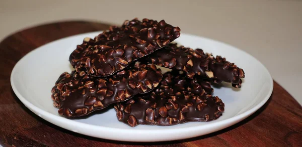 Biscuits carrés au chocolat aux noix sur une assiette ronde blanche . — Photo