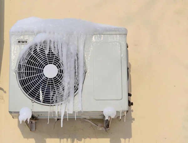 O condicionador coberto de icicles em uma parede amarela — Fotografia de Stock