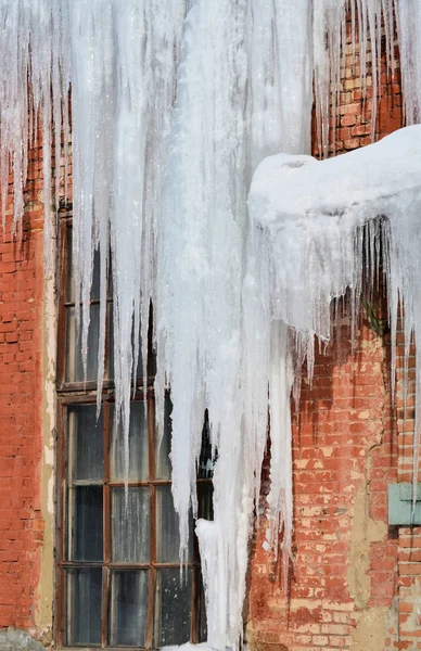 Long, big and dangerous icicles on a brick house roof