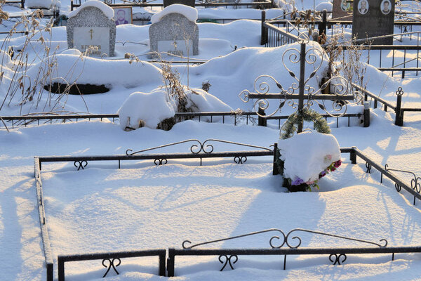 Crosses in a cemetery, monuments of the dead, a cemetery in winter, wreaths, artificial flowers. Russia