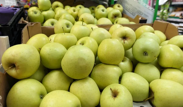 Fresh Golden Delicious juicy whole apples for sale in a store in boxes.