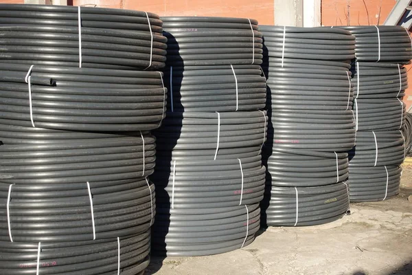 Tubos de plástico preto enrolado armazenados ao ar livre — Fotografia de Stock
