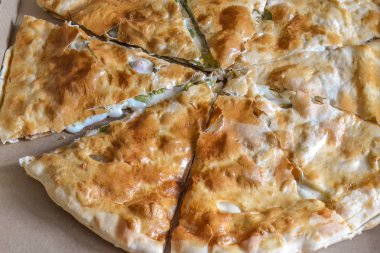 Büyük pizza bir karton kutu içinde parçalarhalinde kesilmiş