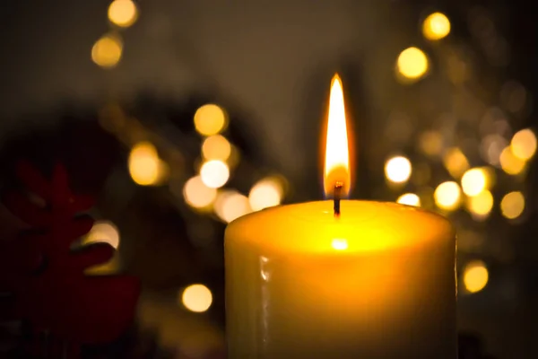 Eine Kerze, die hell in der Dunkelheit vor dem Hintergrund verschwommener Lichter brennt. Romantik, festlicher Abend — Stockfoto