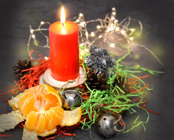 Jul komposition: ett rött ljus brinnande på ett festligt bord på en mörk bakgrund. Pepparkakor, glitter, Garland, mandarin. Jul, nyår, semester — Stockfoto