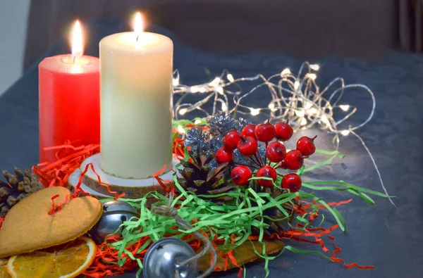 Kerstmis samenstelling: rood en wit brandende kaarsen op een feestelijke tafel op een donkere achtergrond. Peperkoek, klatergoud, Festoon. Kerstmis, Nieuwjaar, vakantie — Stockfoto