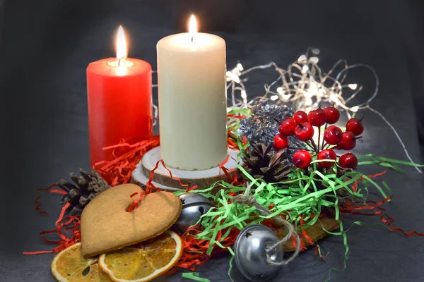 Kerstmis samenstelling: rood en wit brandende kaarsen op een feestelijke tafel op een donkere achtergrond. Peperkoek, klatergoud, Festoon. Kerstmis, Nieuwjaar, vakantie — Stockfoto