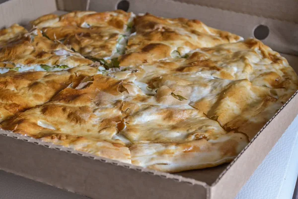 Grande pizza coupée en morceaux dans une boîte en carton — Photo