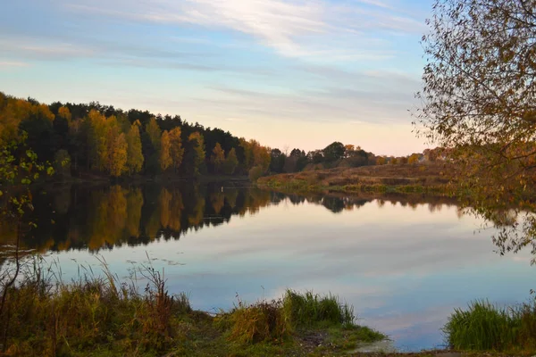 Amanecer en el bosque cerca del lago. El bosque se refleja en el agua. Otoño temprano por la mañana. Rusia —  Fotos de Stock