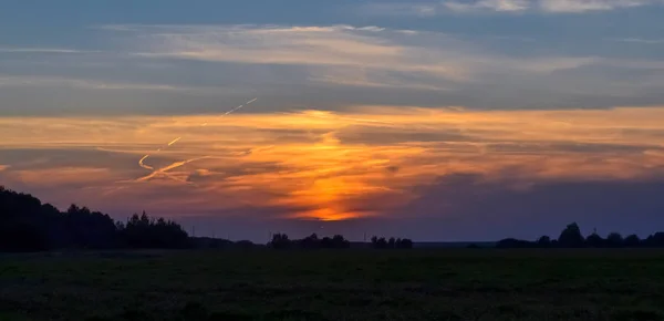 Piękny zachód słońca w polu. Czerwone, żółte, niebieskie niebo. Letni wieczór. — Zdjęcie stockowe