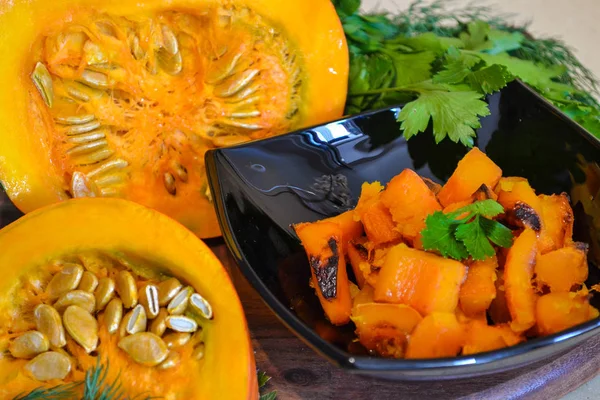 Calabaza al horno en un plato negro y rebanadas de calabaza con verduras. Un delicioso plato de otoño . —  Fotos de Stock