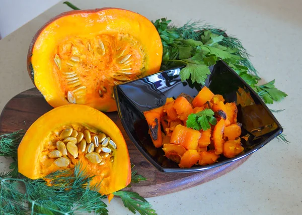 Calabaza al horno en un plato negro y rebanadas de calabaza con verduras. Un delicioso plato de otoño . —  Fotos de Stock