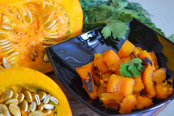 Calabaza al horno en un plato negro y rebanadas de calabaza con verduras. Un delicioso plato de otoño . —  Fotos de Stock