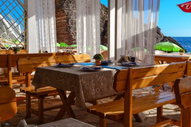 Masa ve sandalyeler denize yakın restoran. Güneşli bir gün yaz var. İnsanlar. Karadağ