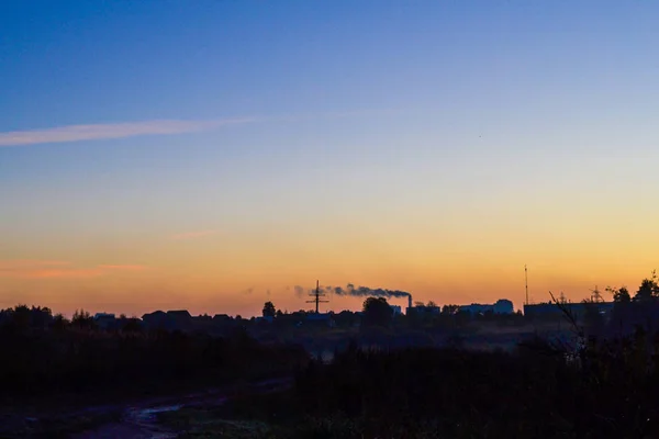 Early morning. The sun has not yet risen. Silhouette of the city. The sky is blue with the yellow at the horizon — Stock Photo, Image