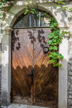 Sarmaşık ile bir taş duvar, kemerli vintage ahşap kapılar