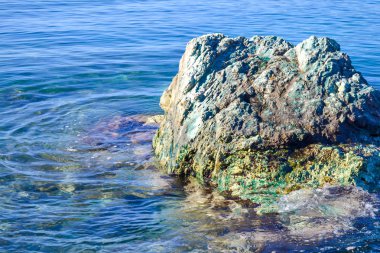 Büyük bir taş suyun üzerinde yükselir. Adriyatik Denizi. Yaz. Dalgalar olmadan sessiz deniz.