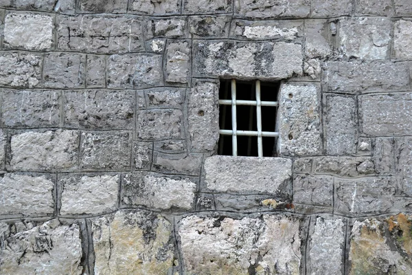 Window with a lattice in the stone wall of the old fortress — Stock Photo, Image